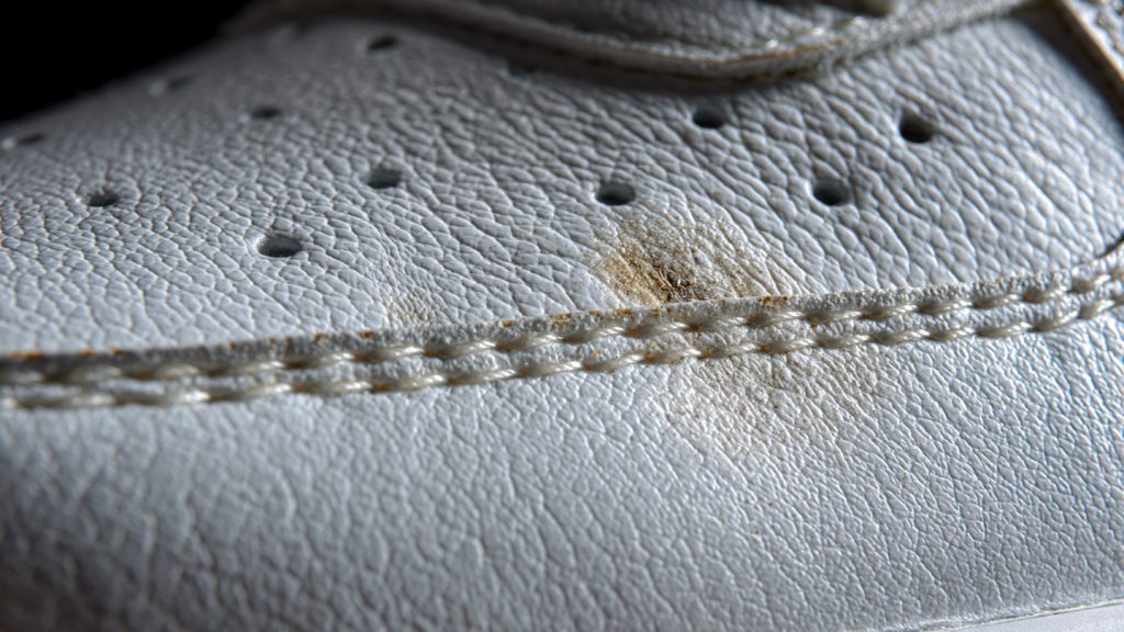 close up texture of white leather sneaker surface showing grain and scuff